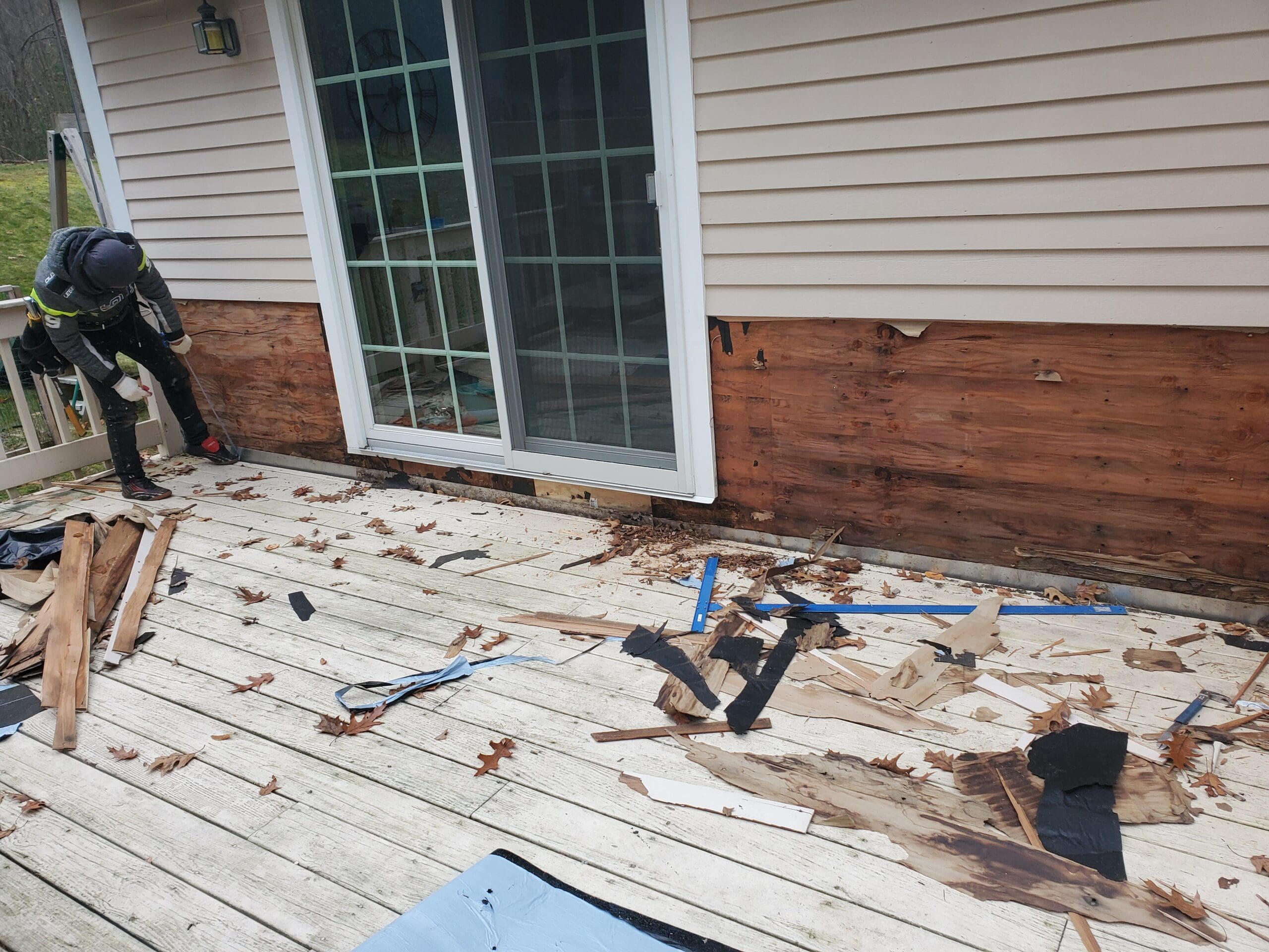 A wooden deck undergoing repair with tools and removed boards scattered.