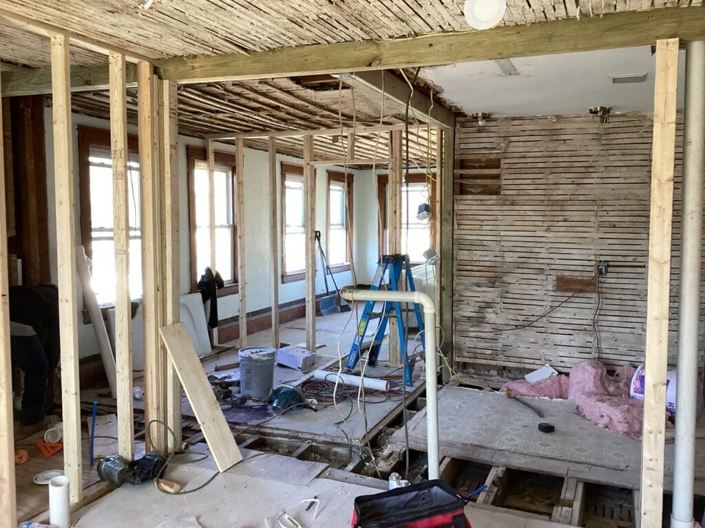 Interior of a house under renovation with exposed wooden beams and construction materials.